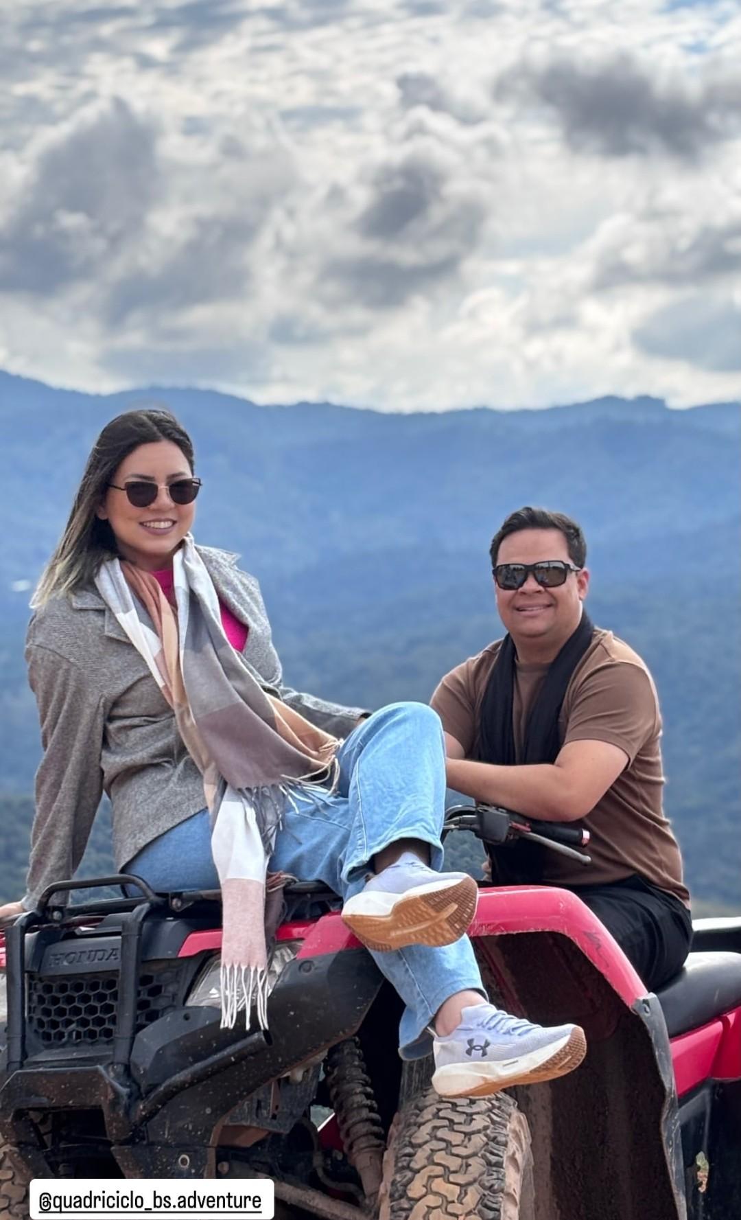 Casal sorrindo sobre quadriciclo com vista para as montanhas